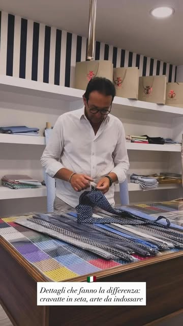 Salvatore Comella lavora tra camicie e tessuti sul banco della sartoria